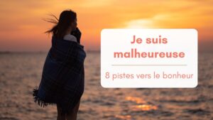 Une jeune femme emmitouflée dans une grosse couverture, de dos, regarde le soleil couchant sur laplage, bannière article "je suis malheureuse, 8 pistes vers le bonheur"