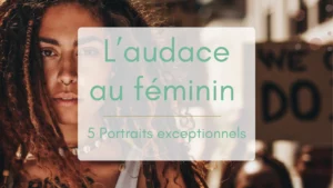 Jeune femme aux longs cheveux en dreadlocks, portant un message contestataire sur son torse, en tête d’une manifestation. Derrière elle, des pancartes affichent des slogans engagés. Une image forte incarnant l’audace au féminin.