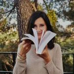 Mylène feuilletant son livre CAP de créer la vie qui te ressemble ? 52 défis pour réenchanter ta vie, avec le sourire